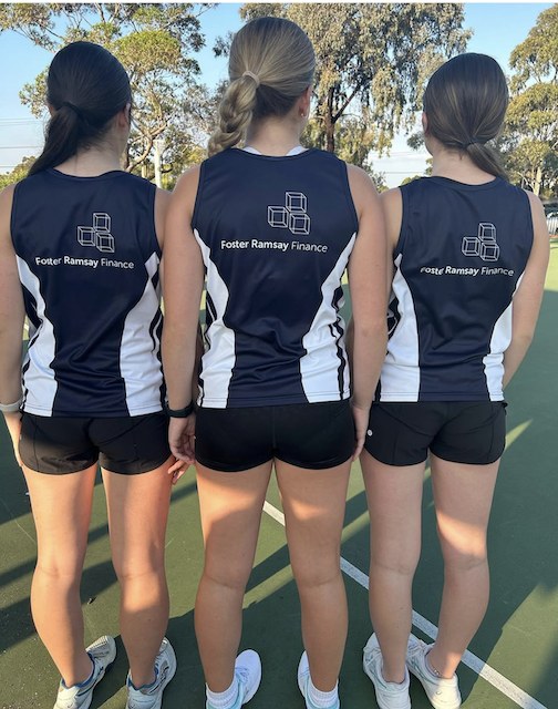 Players wearing netball training uniforms with Foster Ramsay Finance branding