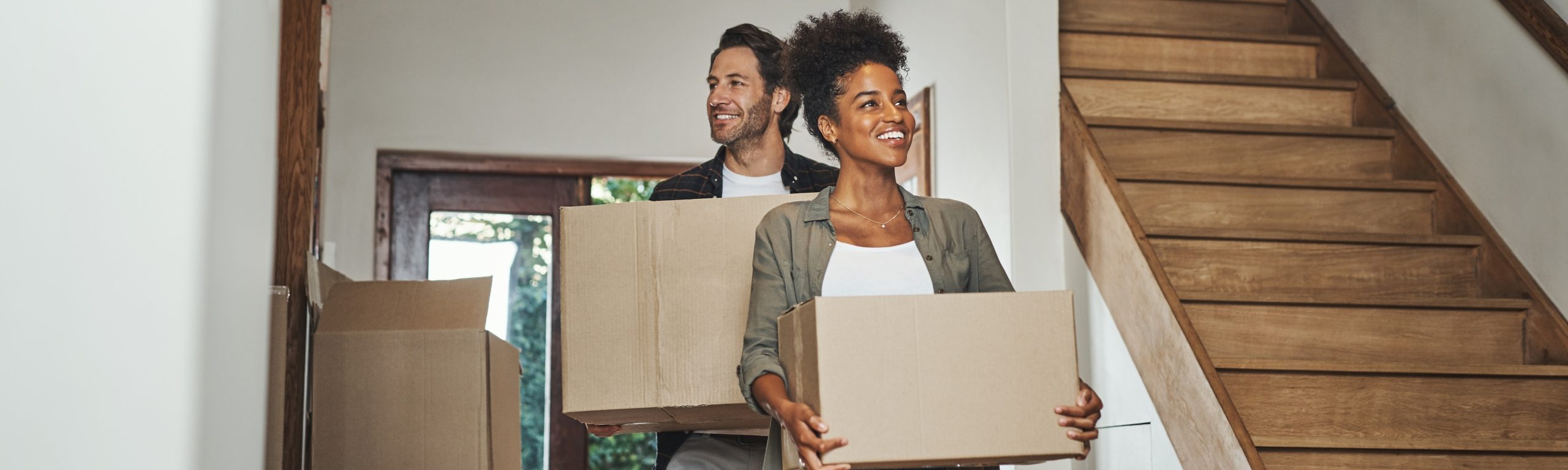 A couple carrying moving boxes into a home